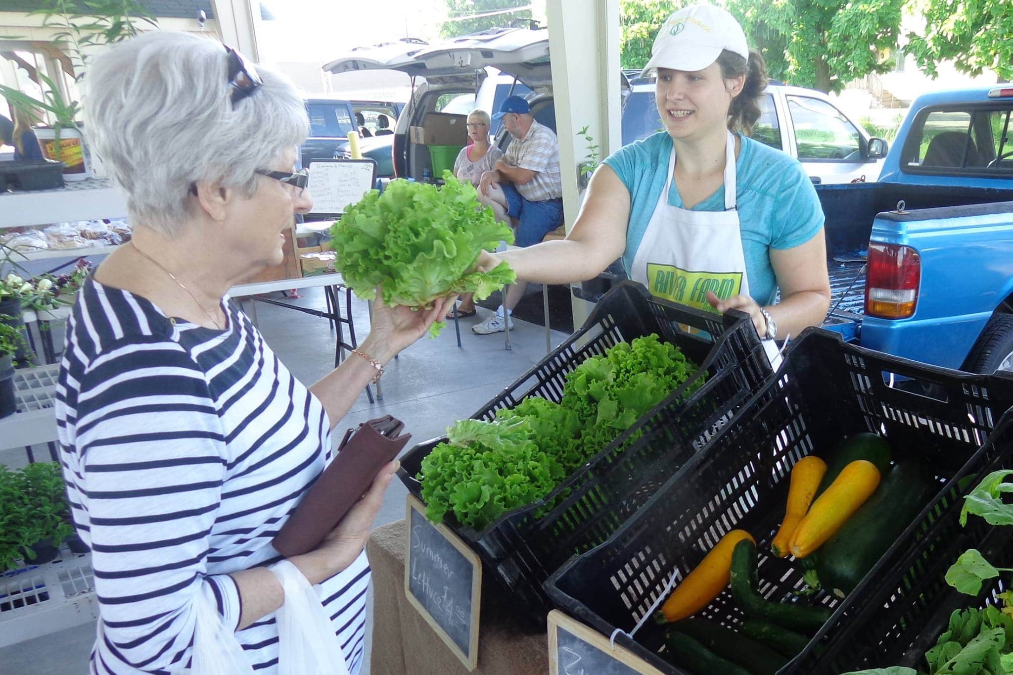 Woman picking out lettuce at the Pittsburg Farmers Market at the Pittsburg Farmer Market Pavilion in Pittsburg, KS.